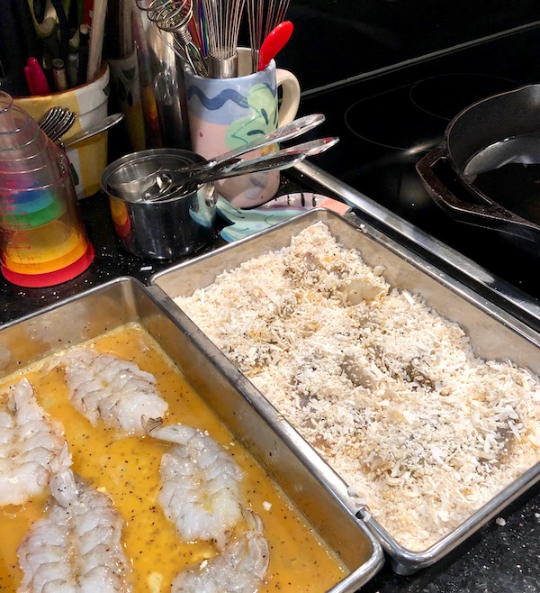Two metal pans holding shrimp, one with egg wash and the other with panko/coconut coating for my Coconut Shrimp with Strawberry Mango Salsa