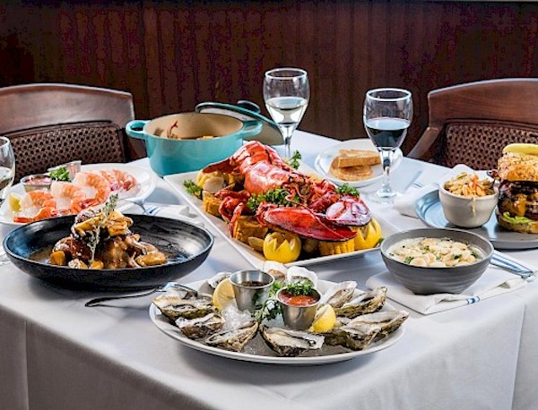 A table covered with a white tablecloth topped with lavish plates of food is part of the Exciting News About Cunard's Queen Mary