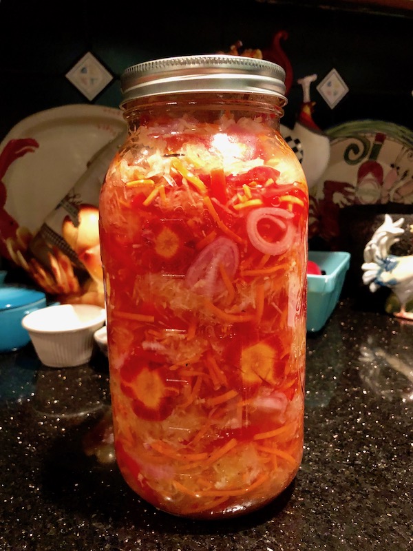 A large quart mason jar filled with shredded salad Green Papaya Salad on a counter