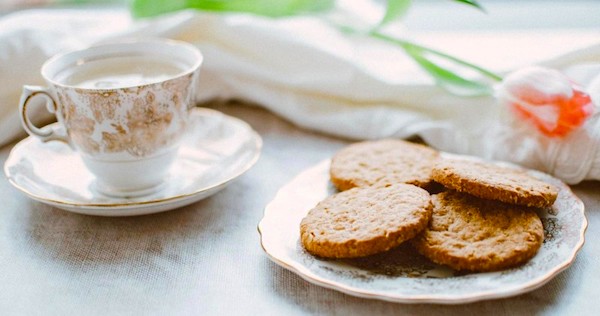 A white and red teacup and a plate of cookies part of the Inn at Hastings Park Wine Dinners