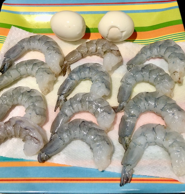 Raw shrimp and 2 hard boiled eggs on a colorful plate waiting to be cooked and added to the Jimmy's Milan Salad