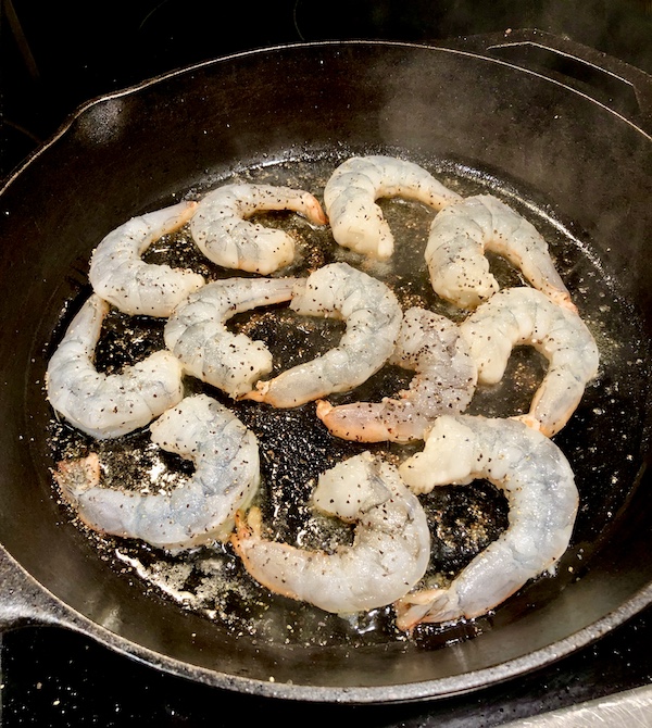 Seasoned shrimp sautéing in a cast iron pan for the Jimmy's Milan Salad