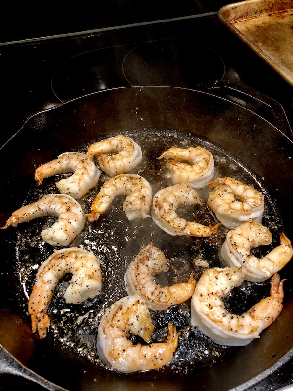 Perfectly cooked shrimp ready to be removed from the cast iron pan.