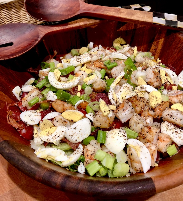 Wood salad bowl filled with salad of shrimp, eggs, and greens to create the Jimmy's Milan Salad