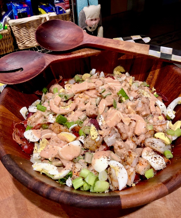 Wooden salad bowl filled with Jimmy's Milan Salad and with servers resting on edge.