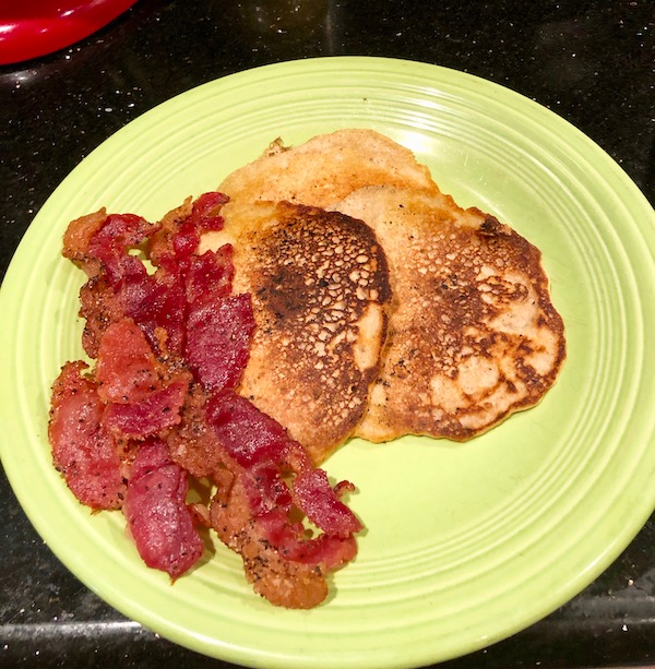 A lime green plate topped with 3 Keto Pancakes and 3 strips of bacon.