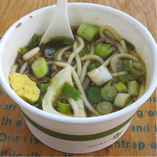 Yakamein Soup with lots of scallions in a paper take out container