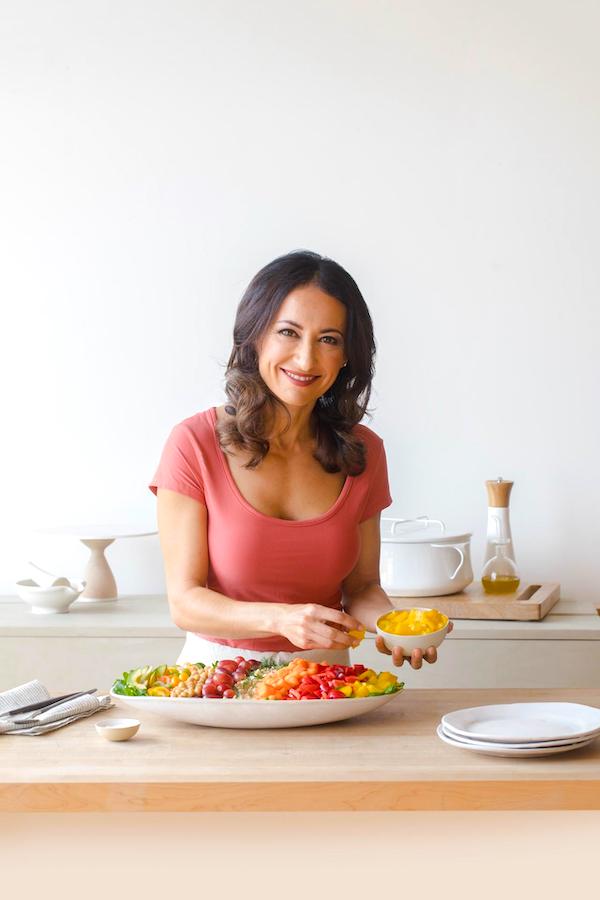 A dark haired woman in a red top preparing food in a white kitchen from Eat Like You Give A Fork
