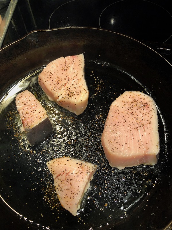 Swordfish steaks cooking in a cast iron pan for my Sicilian Swordfish with Tomatillo Salsa