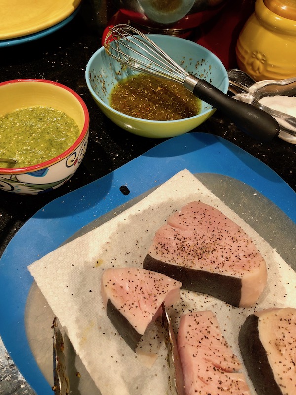 Seasoned Swordfish Steaks on paper towels with two bowls of sauce for my Sicilian Swordfish with Tomatillo Salsa