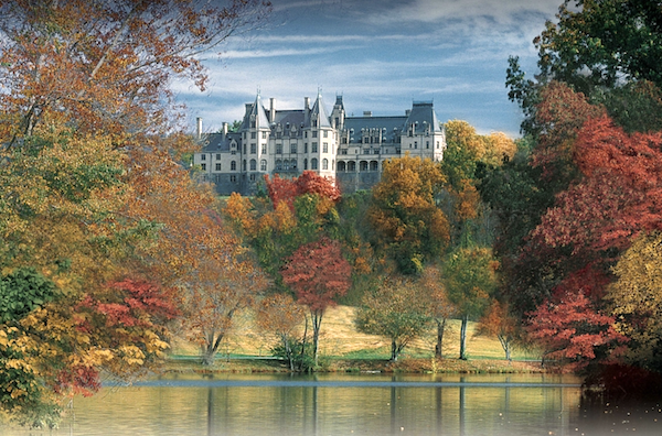 The Biltmore Hosts Downton Abbey Exhibit showing The Biltmore facade from the lagoon with autumnal trees.