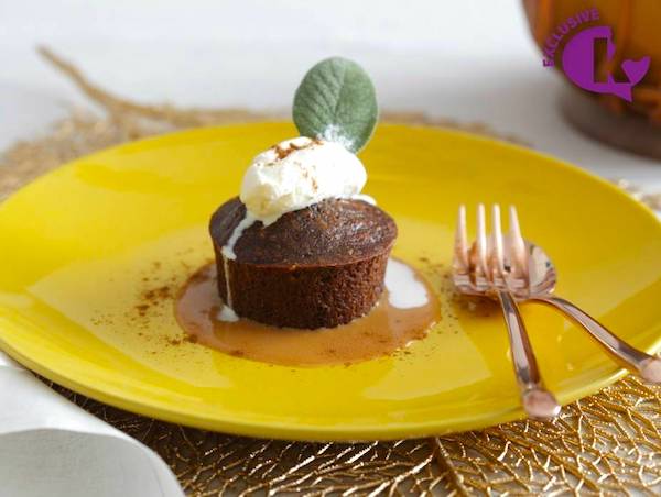 A mustard gold plate topped with a cupcake looking pudding with sauce and whipped cream from Jewish High Holiday Cooking