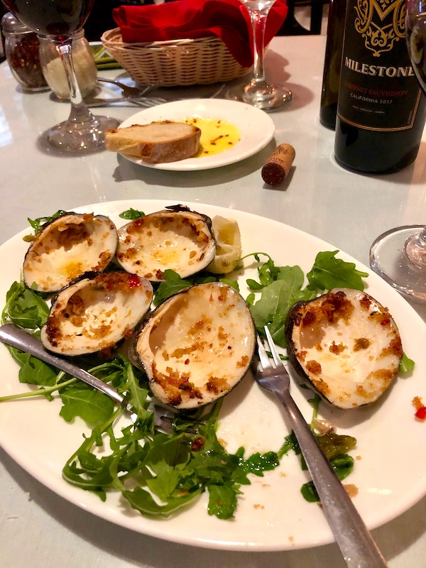 An oval white plate with greens and empty clam shells at Red Room in Ventnor NJ