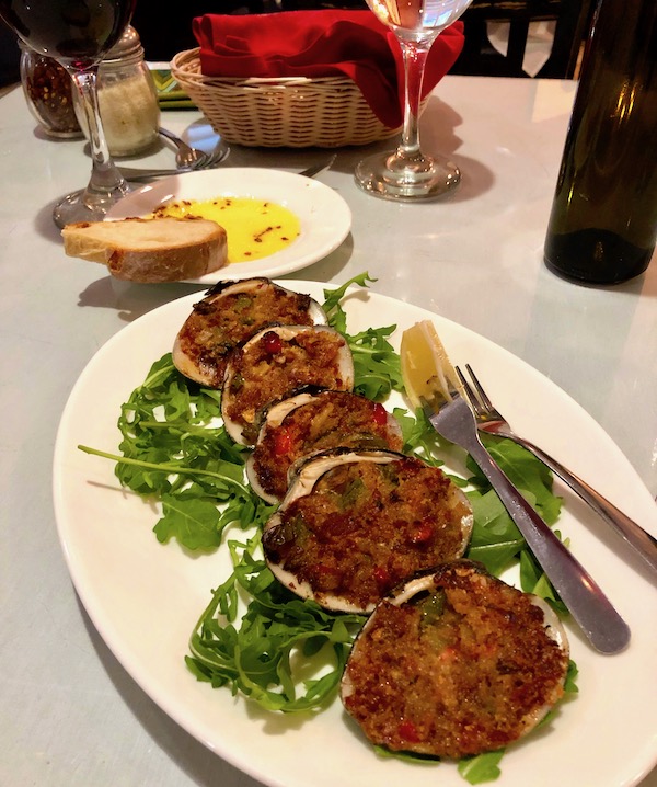 An oval white plate topped with greens and 6 clam shells filled with brown stuffing at Red Room in Ventnor NJ