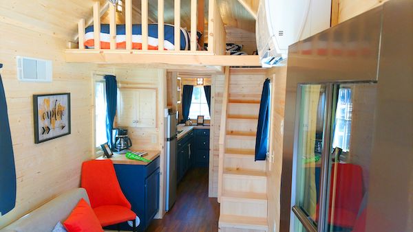 A red chair and wood stairs leading to the sleeping loft in a tiny house from Authentic Oktoberfest - No Passport Required