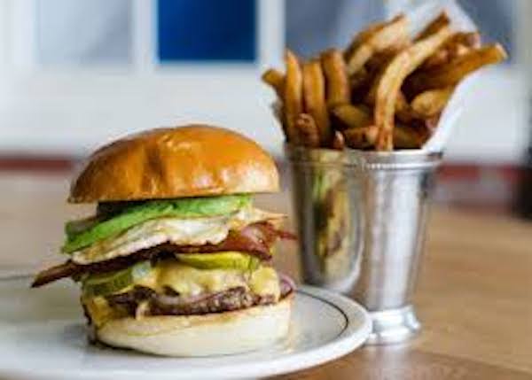 A huge burger in a bun with a metal cup of fries from Fall Adventures In Asheville NC