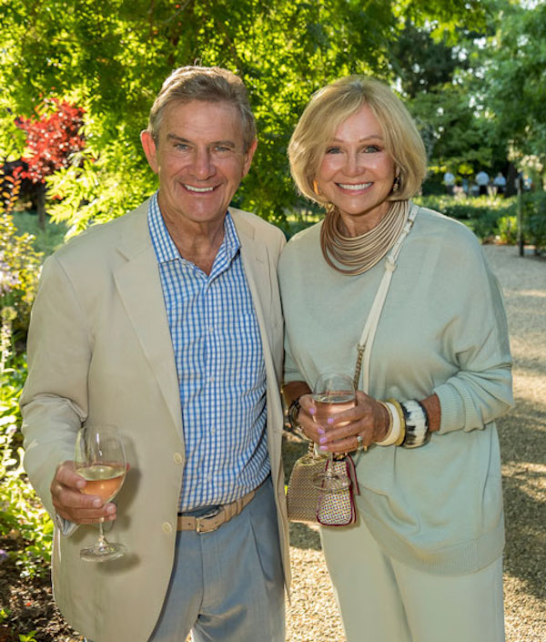 A couple standing in front of grape vines from Walt Wines New Tasting Room