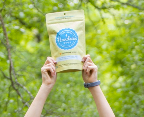A woman's hands holding up a bag of Handzies Wipes from Fun Camping Essentials