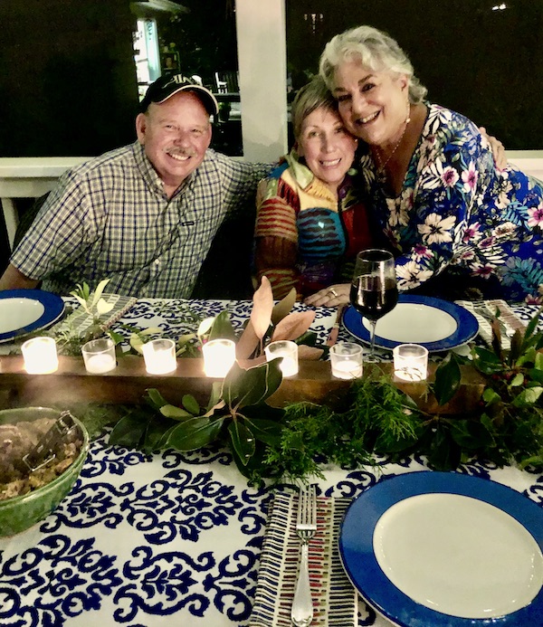 A man and 2 women at a beautifully set table with votives