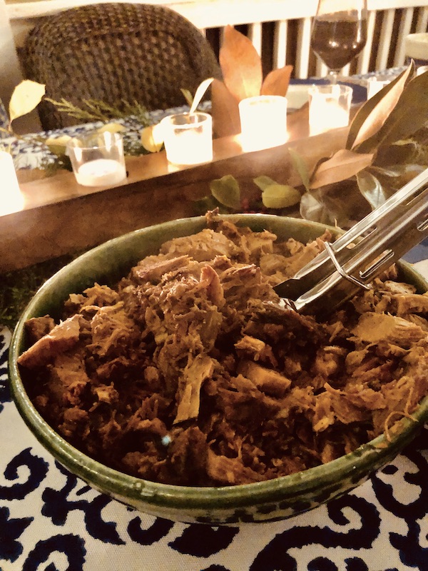 A big bowl of pulled pork with tongs.