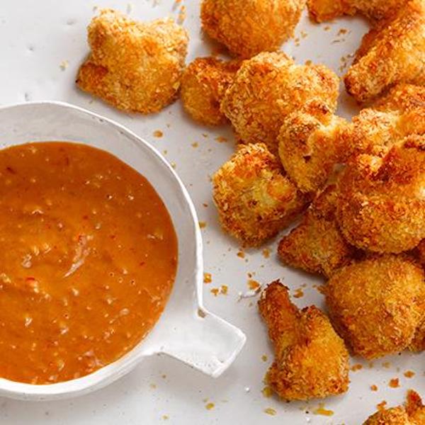 A white bowl of orange sauce with fried cauliflower alongside as the perfect appetizer before a Chicken Breast Tahini Drizzled Hero for Super Bowl