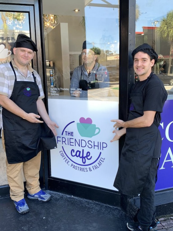 Two young men pointing to a sign for Friendship Café on Las Olas