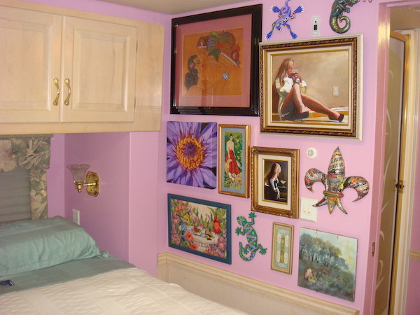 An RV bedroom with mauve walls and artwork from Happy Campers