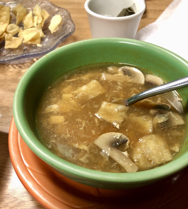 An olive soup bowl filled with Chinese Hot and Sour soup on a wood table made us Happy Campers.