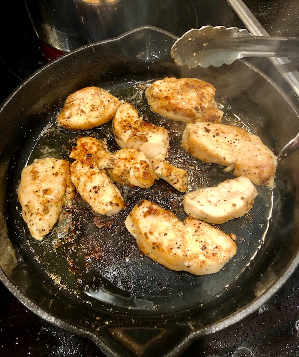 Golden brown chicken slices in a cast iron pan
