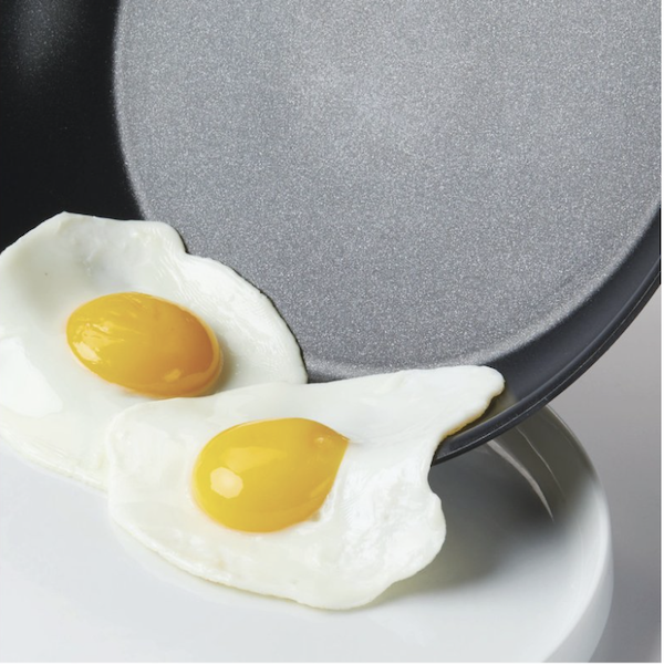 Bring Wellness to the Kitchen with a non-stick pan that two eggs are sliding off onto a plate.