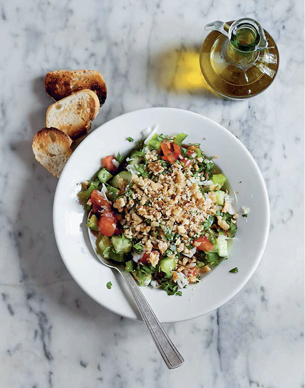 A white bowl filled with chopped salad on a marble surface with bread and oil from Istanbul Cult Recipes