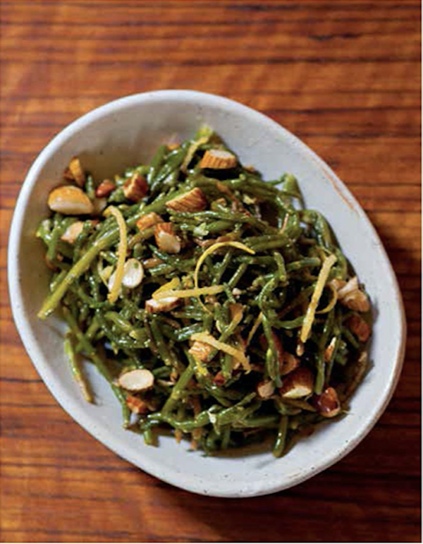 A bowl of green sea beans with almonds on a wood table from Istanbul Cult Recipes