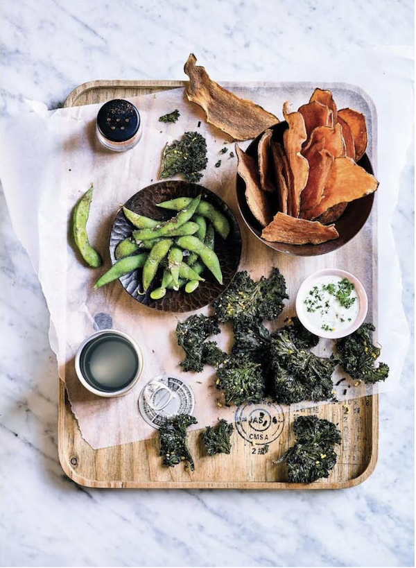 A wood cutting board topped with sweet potato crisps, edamame, and other condiments from My Asian Kitchen