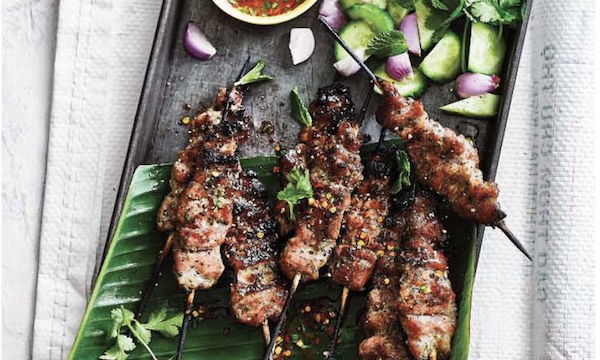 A black platter topped with pork skewers, a bowl of sauce and scallions from My Asian Kitchen