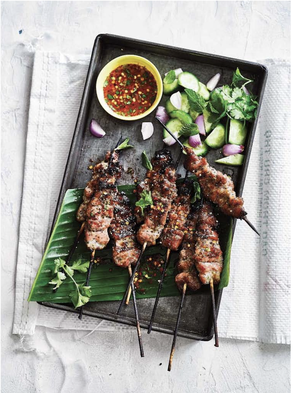A black platter topped with pork skewers, a bowl of sauce and scallions from My Asian Kitchen