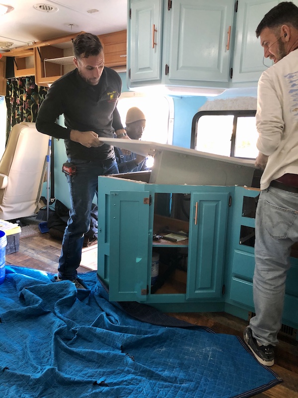 A white countertop being installed on teal base cabinets from Our RV Renovations Update