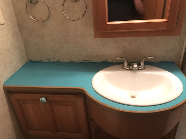 An RV bathroom vanity with teal countertop from Our RV Renovations Update