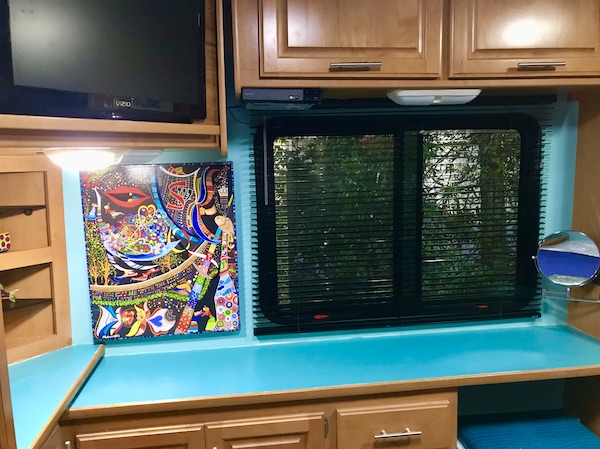 A turquoise and wood desk. a window with black mini-blinds and a piece of art from Another RV Renovations Update