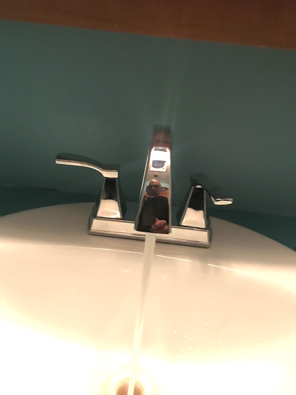 A white sink with chrome faucet and water running from Another RV Renovations Update