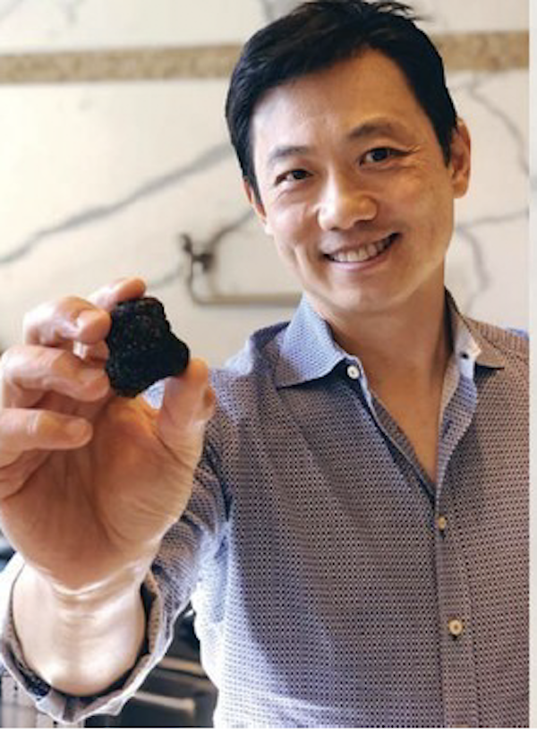 A man in a blue shirt holding a black truffle from post First Burgundy Truffle Harvest in America