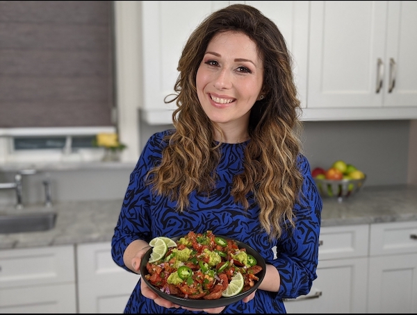 A woman holding a platter of food for Passover 2020