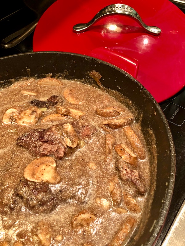 An uncovered braising pan filled with cooked meat, vegetables and gravy for Red Wine Braised Beef
