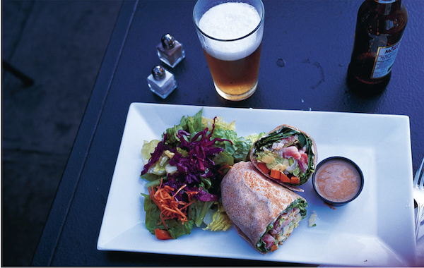 A white rectangular plate topped with a veggie wrap, sauce and a salad from Los Angeles Cult Recipes