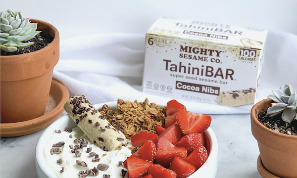 A bowl filled with strawberries, yogurt, tahini bar, granola and cocoa nibs from Yummy Tahini Bars