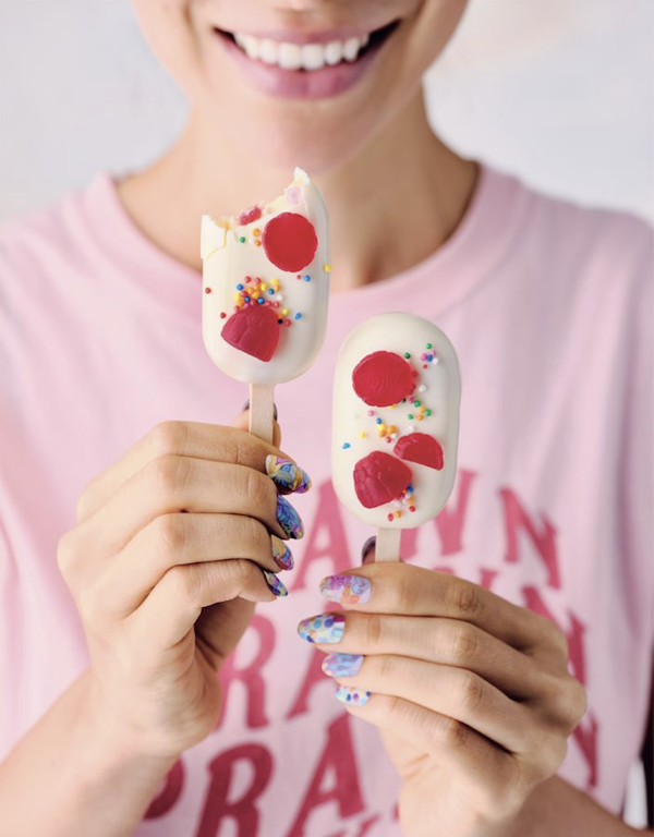 A woman holding a pair of white and red cake pops from Bake Australia Great