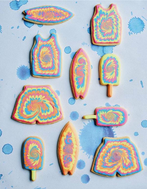 An assortment of tie dye cookies shaped like tank tops, shorts and surf boards from Bake Australia Great