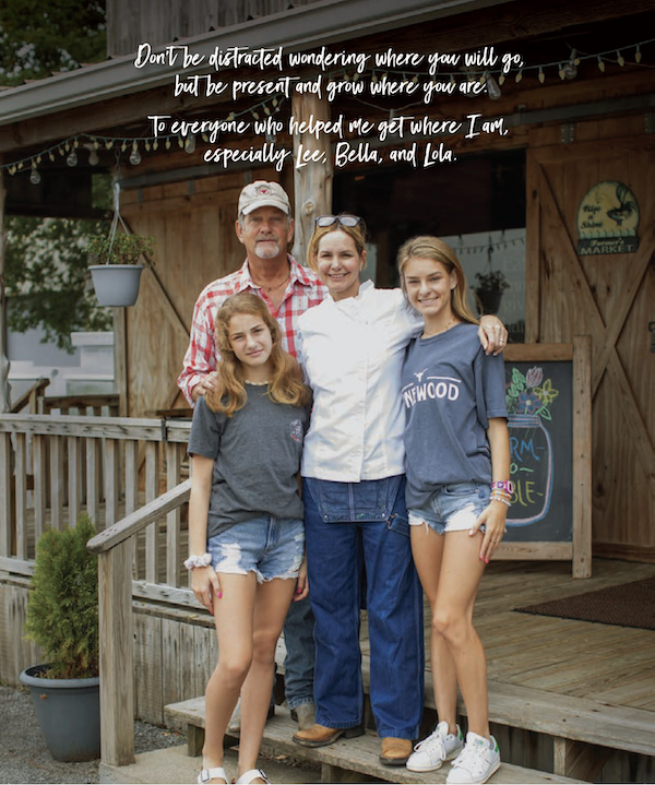 A chef with her husband and two daughters in front of a rustic restaurant.