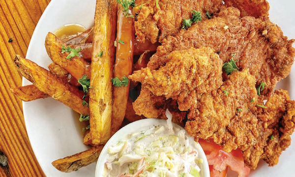 A white plate topped with battered fried pork and fries with coleslaw from My Pinewood Kitchen
