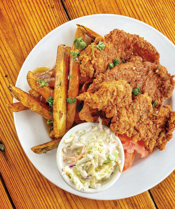 A white plate topped with battered fried pork and fries with coleslaw from My Pinewood Kitchen