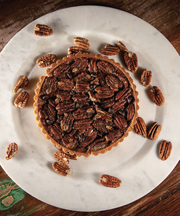A white plate topped with a small pecan pie from My Pinewood Kitchen